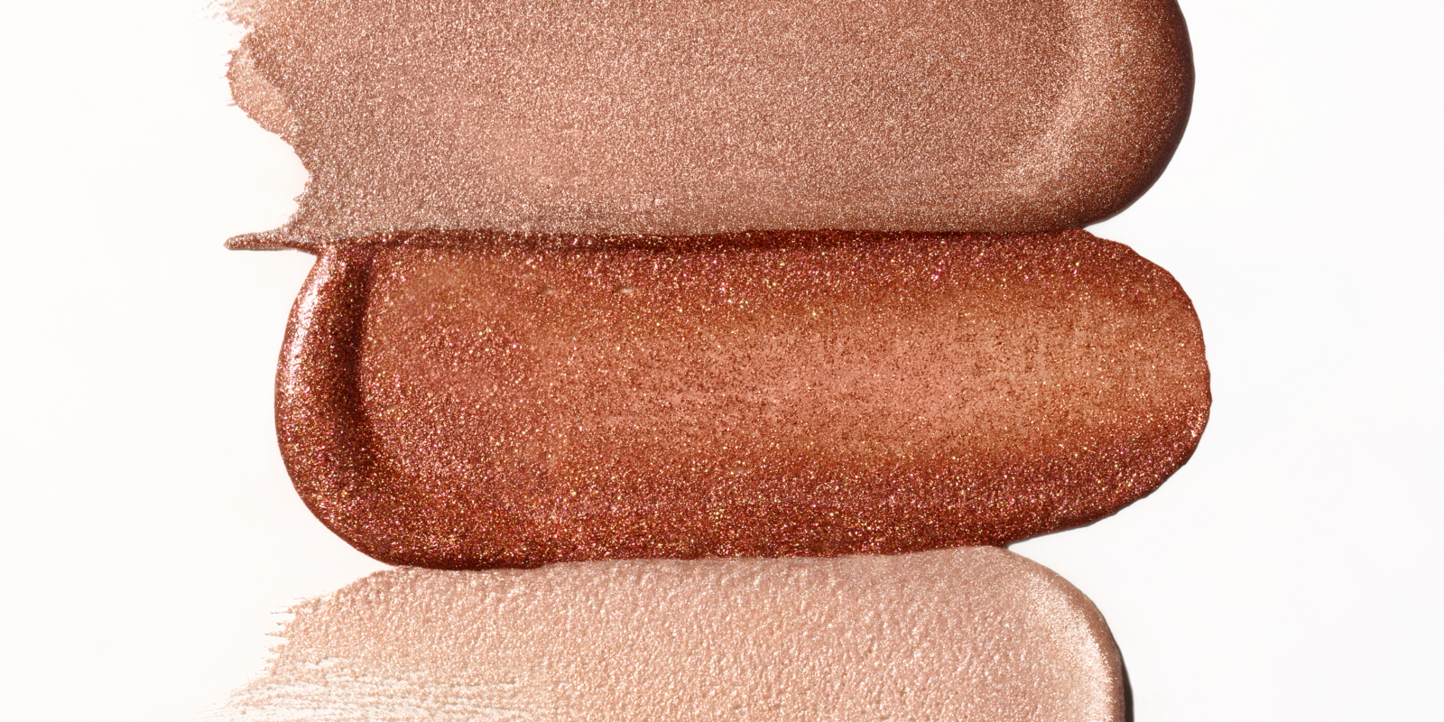 Drie verschillende kleuren oogschaduw worden op een witte achtergrond getoond, geschikt voor oogmake-up.